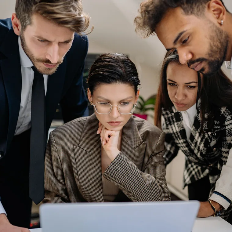 A small team reviewing work together around a laptop
