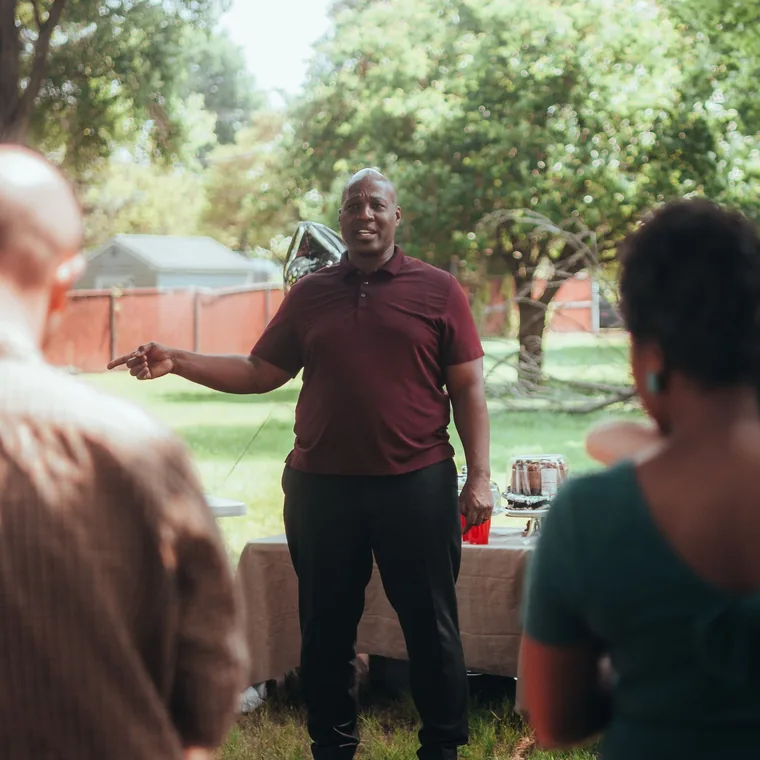 A leader speaking to a small group gathered outdoors