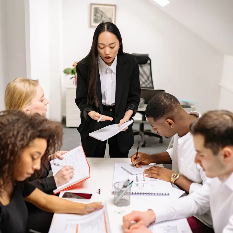A leader standing to address a team gathered around a table